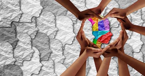 photo of hands holding a rainbow colored profile of a face in a sea of gray faces